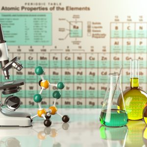 Microscope and glass flasks in front of periodic table.