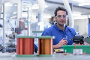 Electronics engineer working with tools and copper wire.