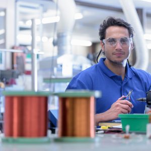 Electronics engineer working with tools and copper wire.