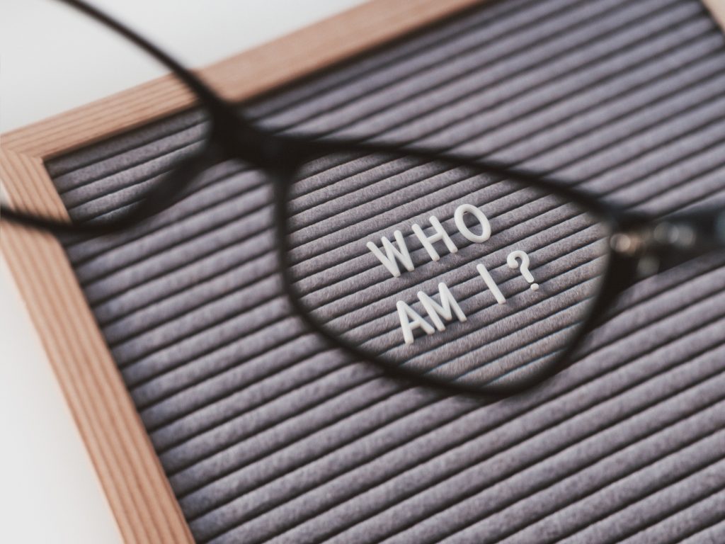 Letters on board spelling Who am I? viewed though glasses frame.