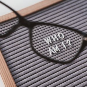 Letters on board spelling Who am I? viewed though glasses frame.