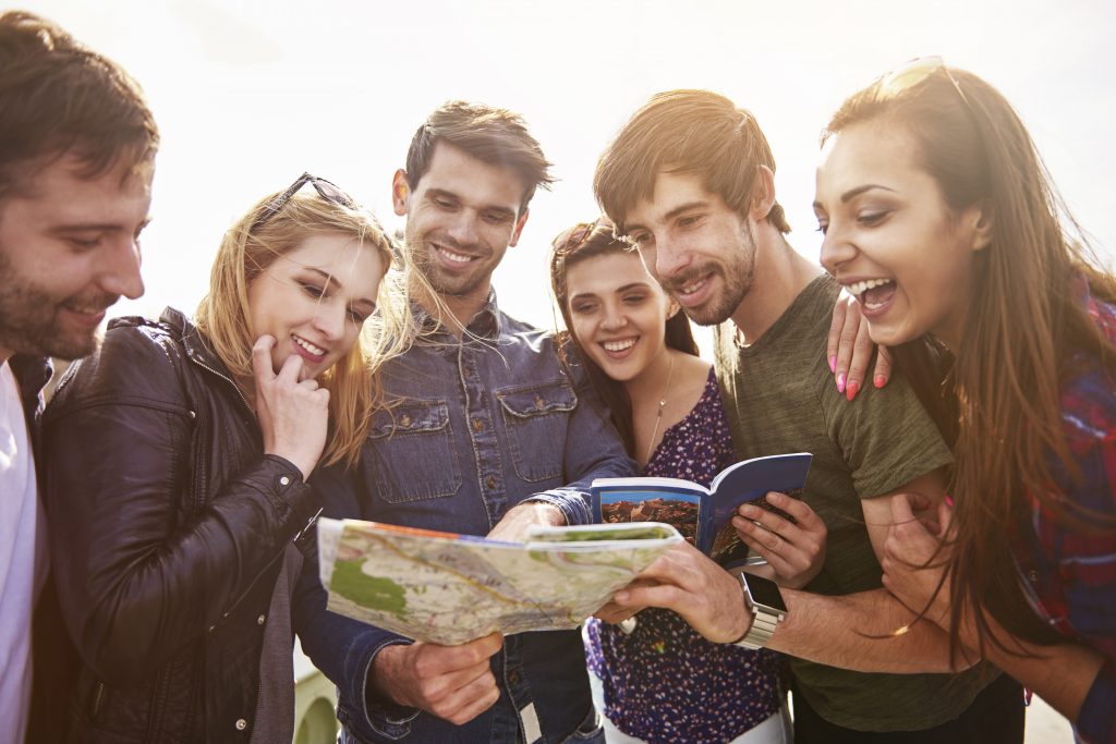 Group of happy people looking at travel guide and map.