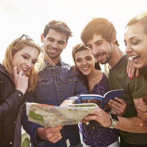 Group of happy people looking at travel guide and map.