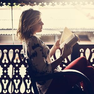 Woman reading a book on a balcony.