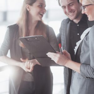 Three business people looking at clipboard.