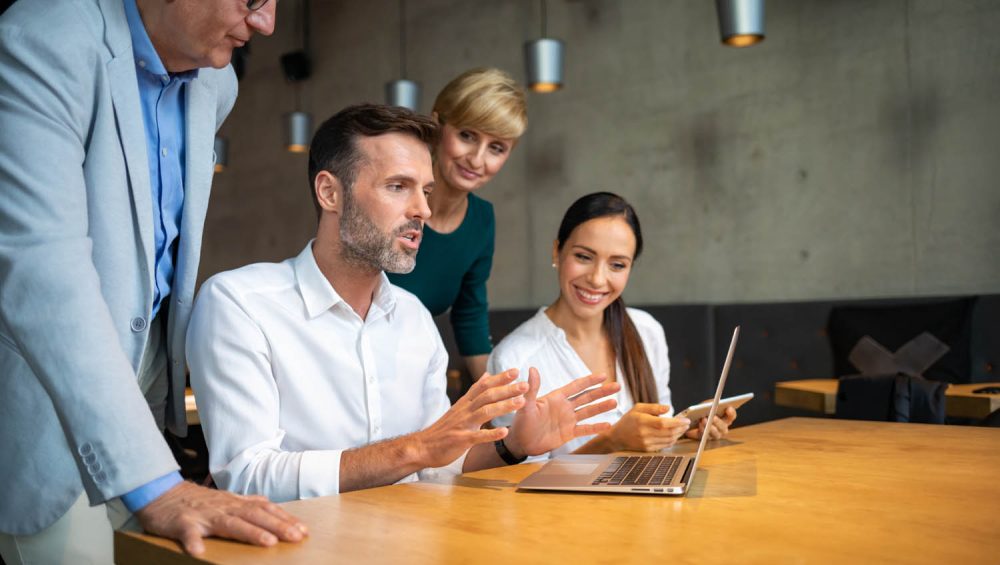 Man in front of laptop talking to staff