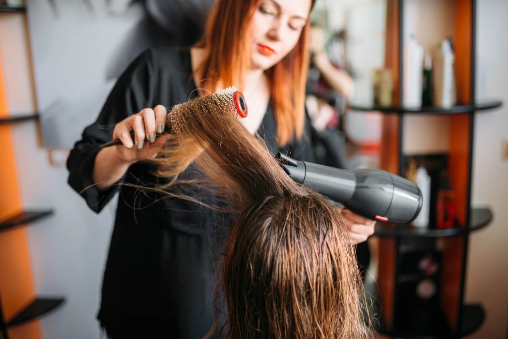 Woman drying hair in salon.