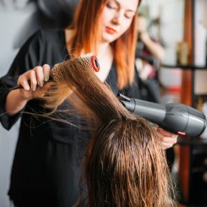 Woman drying hair in salon.