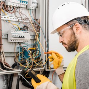 Electrician testing electrical fuse box.