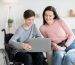 Teen in wheelchair showing woman something on laptop.