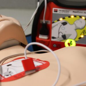 Close up of first aid mannequin with defibrillator machine attached.