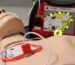 Close up of first aid mannequin with defibrillator machine attached.