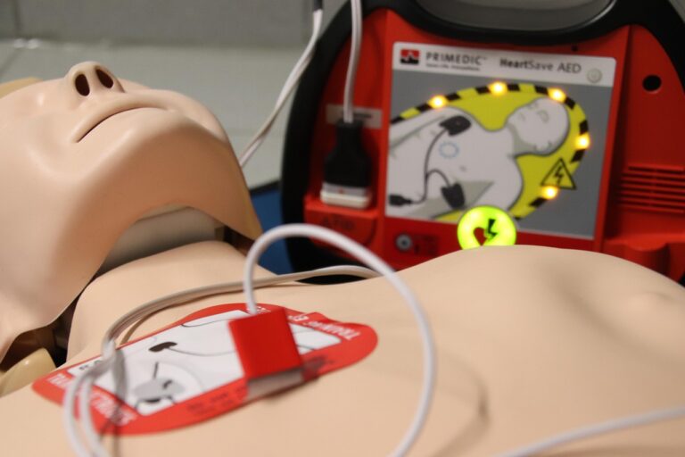 Close up of first aid mannequin with defibrillator machine attached.