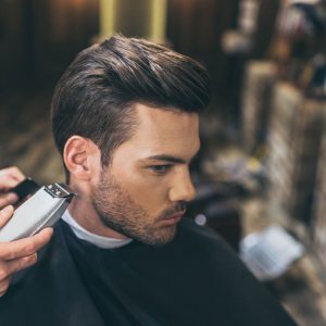Man having hair cut with clippers in barbers.