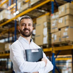 Man holding folder in warehouse.