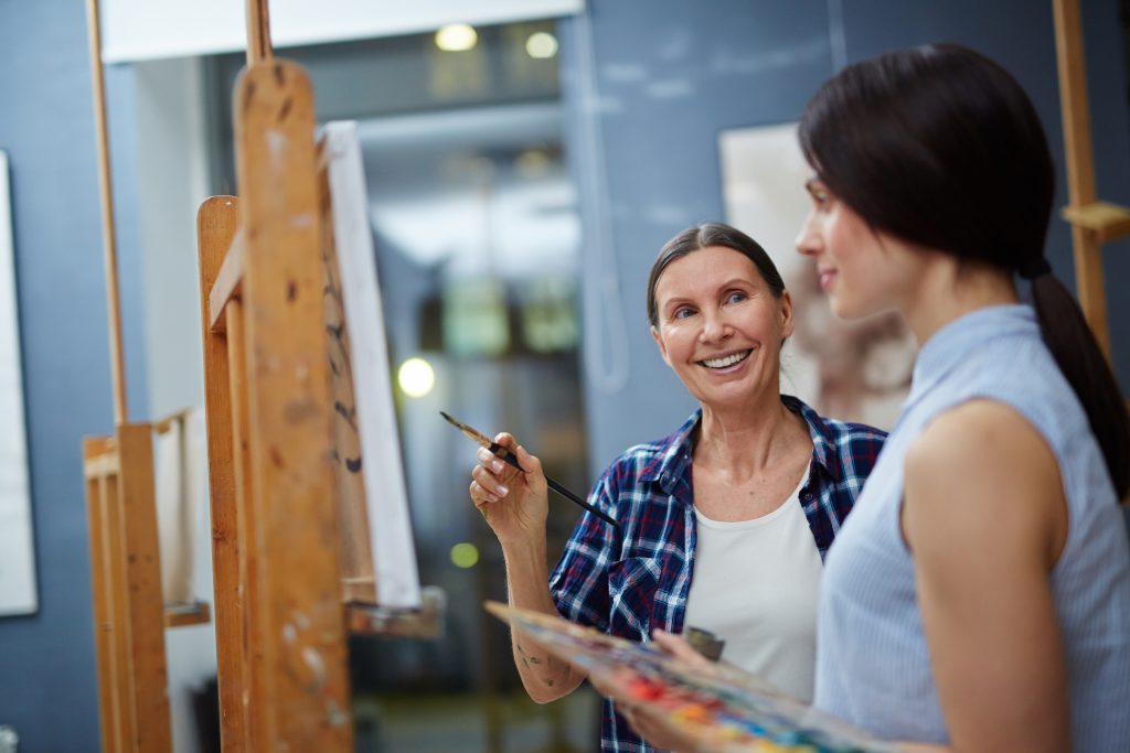 Artist teaching student to paint.