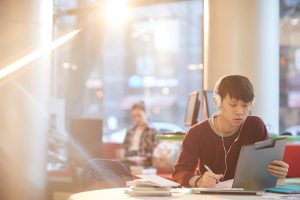 Learner wearing headphones studying in library