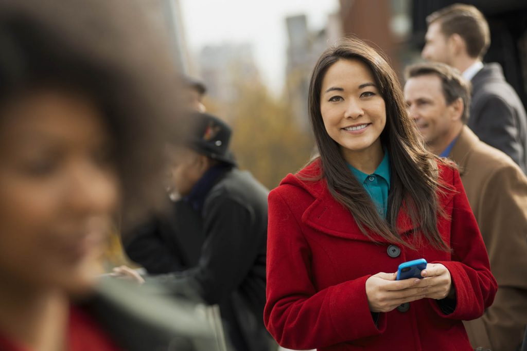 Person in red coat using phone in crowd