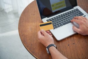 Hands holding a credit card and typing into laptop