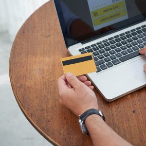 Hands holding a credit card and typing into laptop