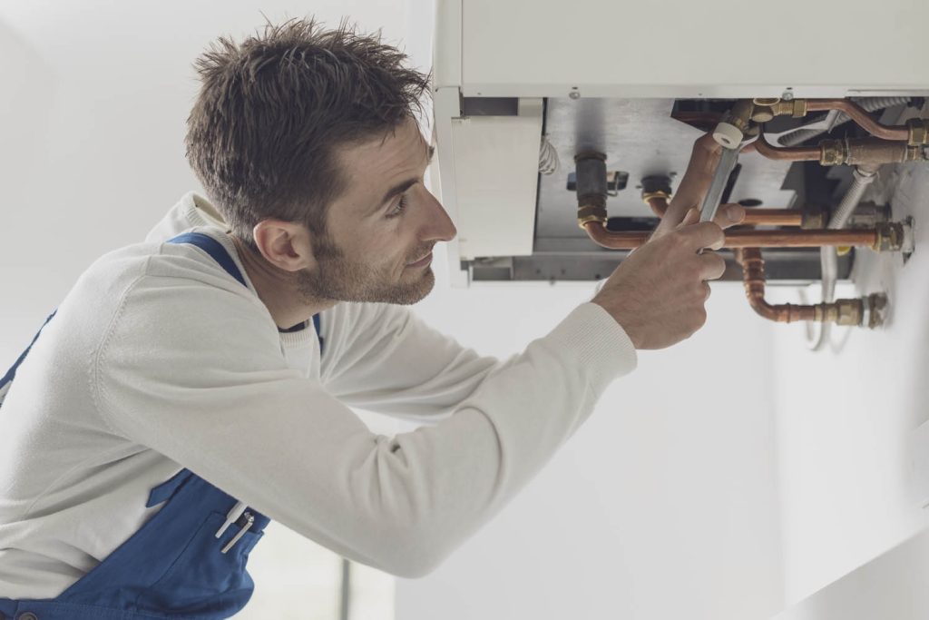Man fixing underside of gas boiler