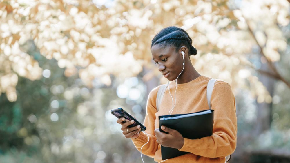 Person wearing headphones and looking at phone