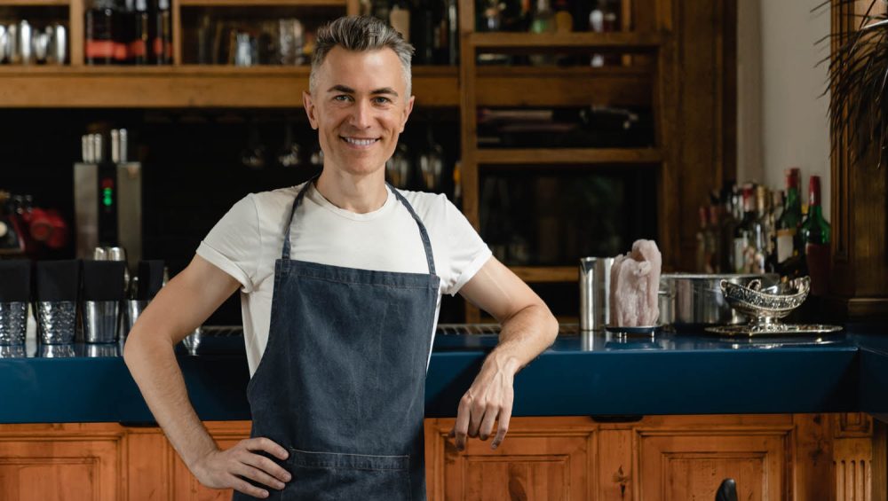 Person wearing apron standing in front of bar