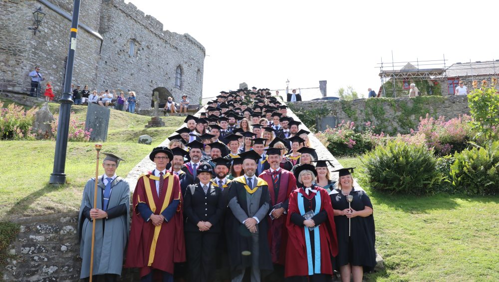 Group of staff and students at graduation on steps
