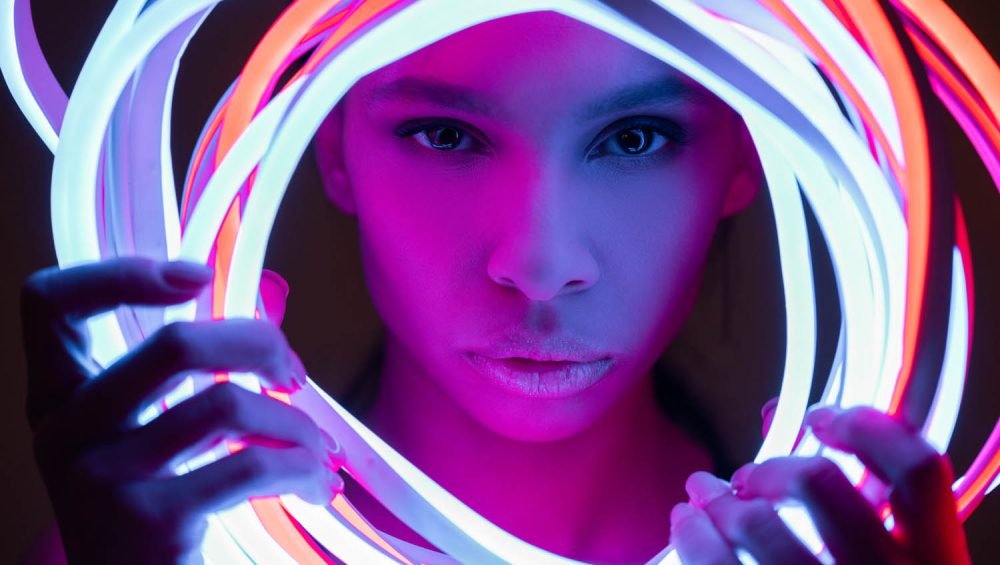 close up of face holding neon tubes