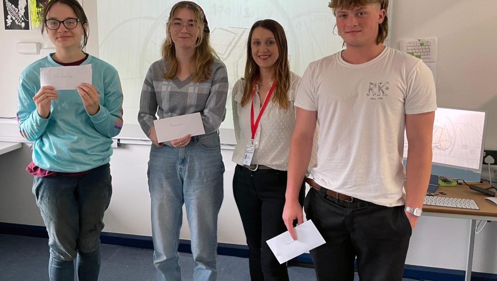Four learners holding prize envelopes.