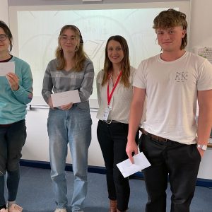 Four learners holding prize envelopes.