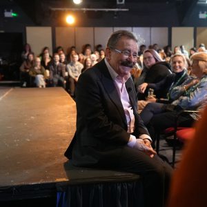 Professor Winston sat on Merlin Theatre stage smiling at audience during a Q&A