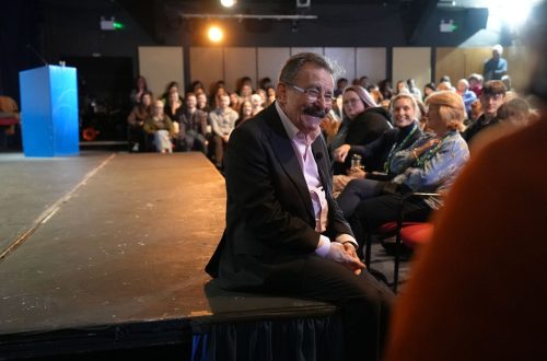 Professor Winston sat on Merlin Theatre stage smiling at audience during a Q&A