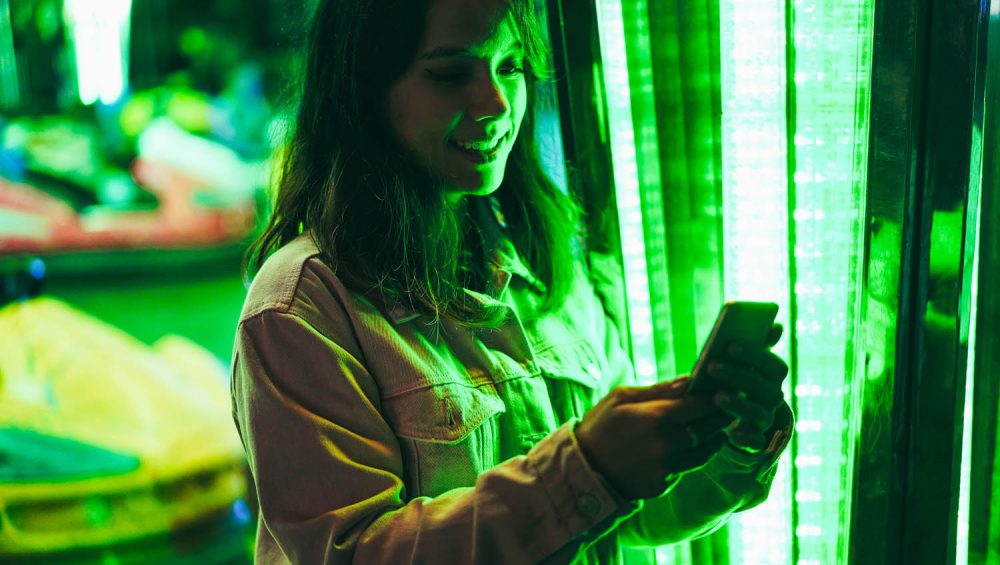 Happy girl using mobile phone at amusement park