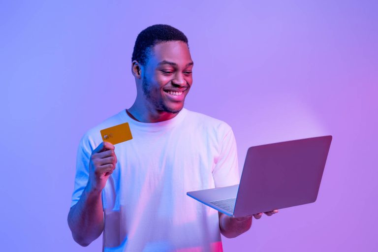 Happy man holding credit card and laptop