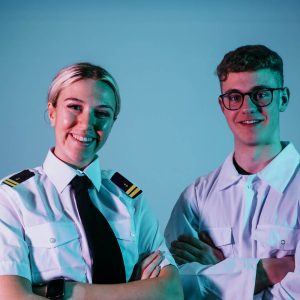 Two students against blue background wearing maritime uniforms.