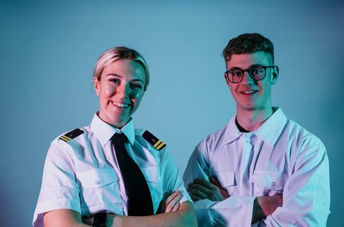 Two students against blue background wearing maritime uniforms.