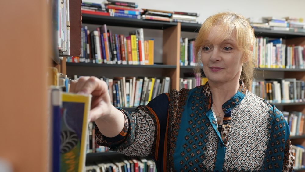 Pembrokeshire College Lecturer Sarah King looking at books in the College Library