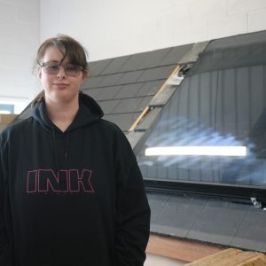 Learner Amy Wilson stands smiling in front of solar panels