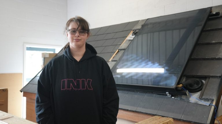 Learner Amy stands smiling in front of solar panels
