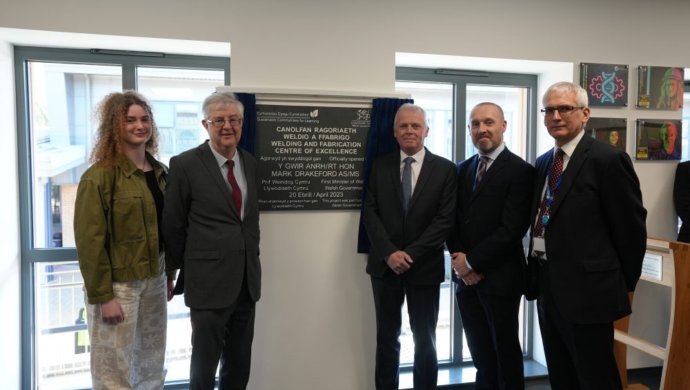 First Minister Mark Drakeford with Pembrokeshire College Principal Barry Walters, Nick Revell, Iwan Thomas and Engineering learner Rhiannon Chapham stood beside the Welding and Fabrication Centre of Excellence Plaque