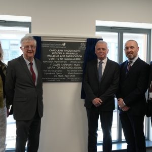 First Minister Mark Drakeford with Pembrokeshire College Principal Barry Walters, Nick Revell, Iwan Thomas and Engineering learner Rhiannon Chapham stood beside the Welding and Fabrication Centre of Excellence Plaque