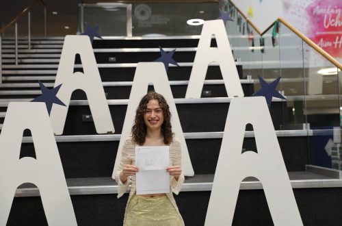 Madeleine Draycott holding results, large a's in background on stairs.