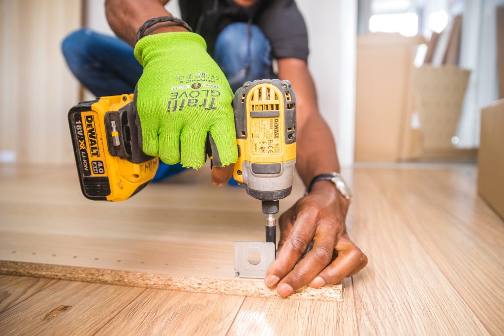 person using electric screwdriver to attach a hinge