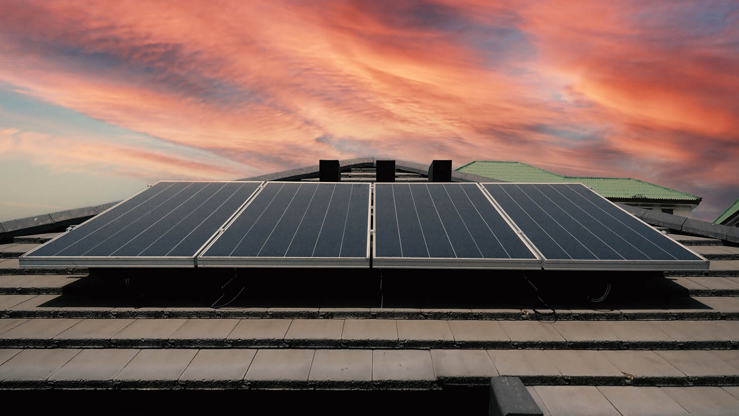 Solar roof power plant on the roof of a residential building with sunrise behind.