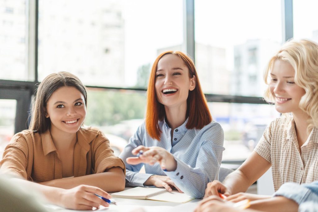 Positive smiling red haired school teacher or tutor explaining something studying, language learning