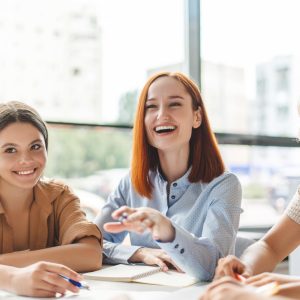 Positive smiling red haired school teacher or tutor explaining something studying, language learning