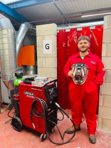 student holding welding helmet in workshop