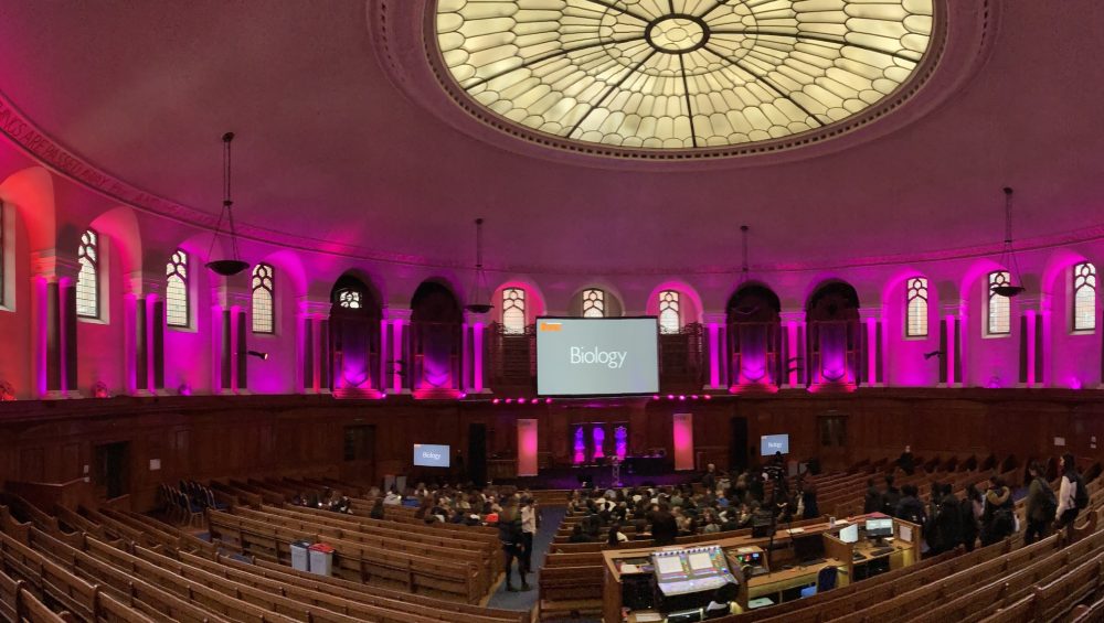 Inside the Emmanuel Centre, London. Pink lighting with rows of seats.