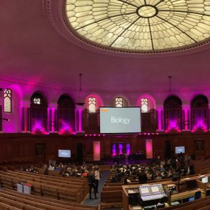 Inside the Emmanuel Centre, London. Pink lighting with rows of seats.